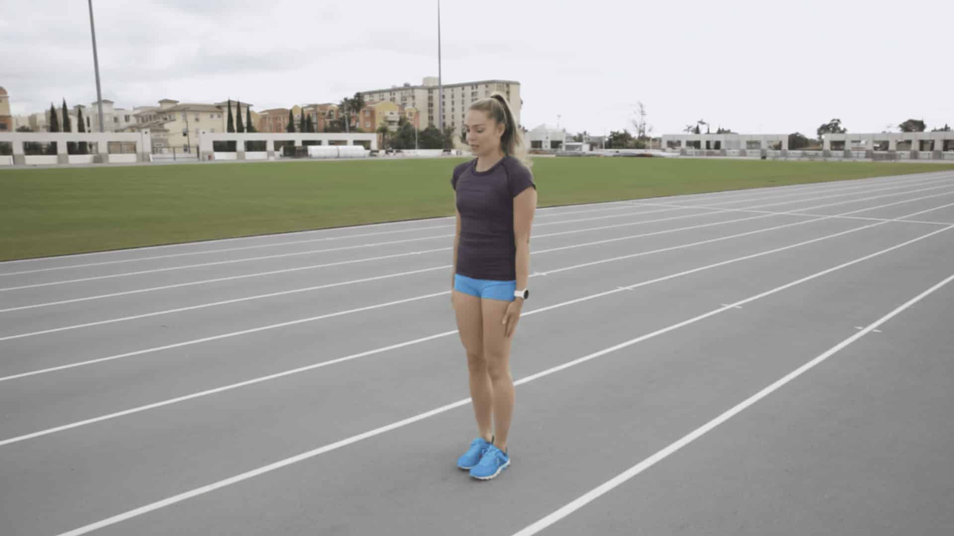 female athlete preparing to extend leg and snap foot down under hips during sprint drill on track