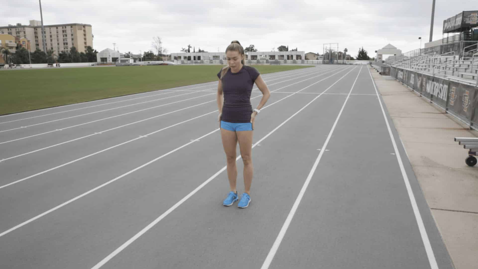 female athlete standing tall on track demonstrating proper posture and hip alignment during sprint drill