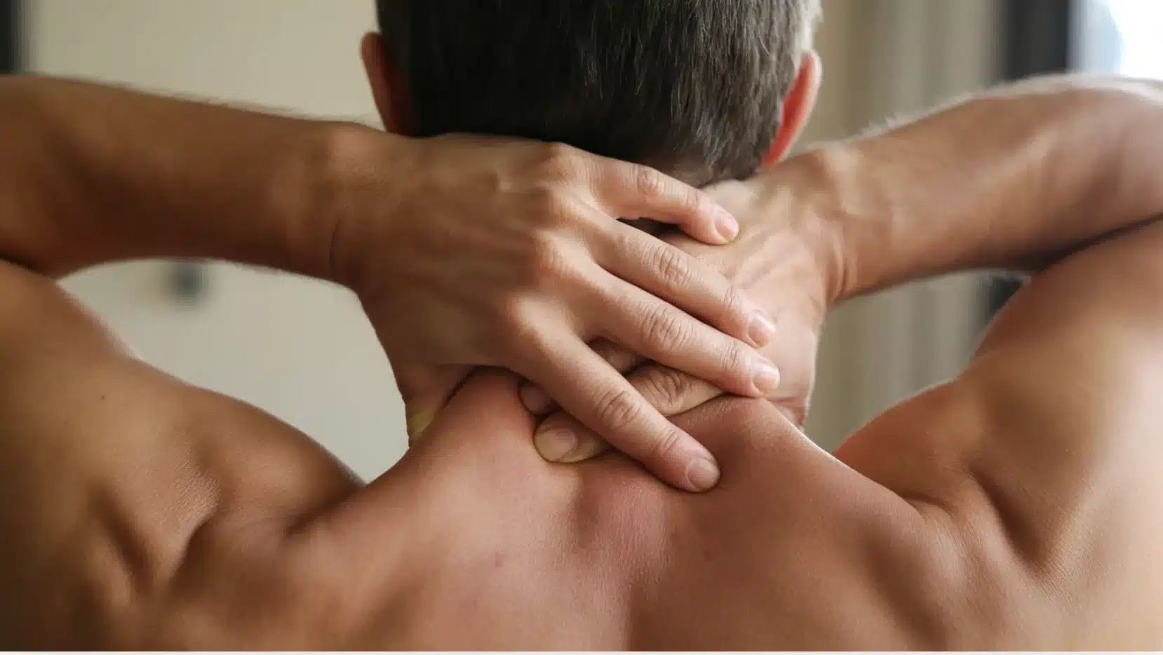 a person massaging their neck by clasping their hands behind their head and applying pressure to relieve tension