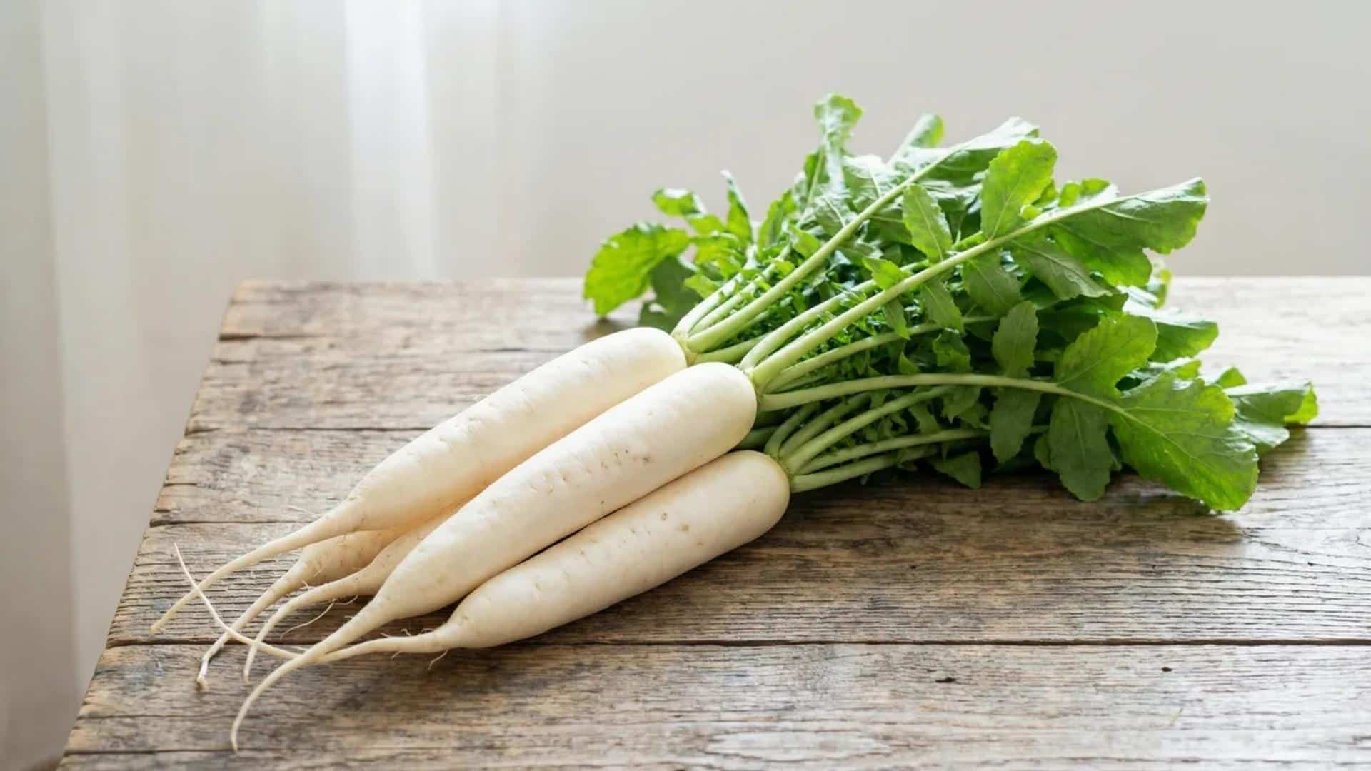 fresh whole white radishes with leafy green tops placed on a rustic wooden table in soft natural light
