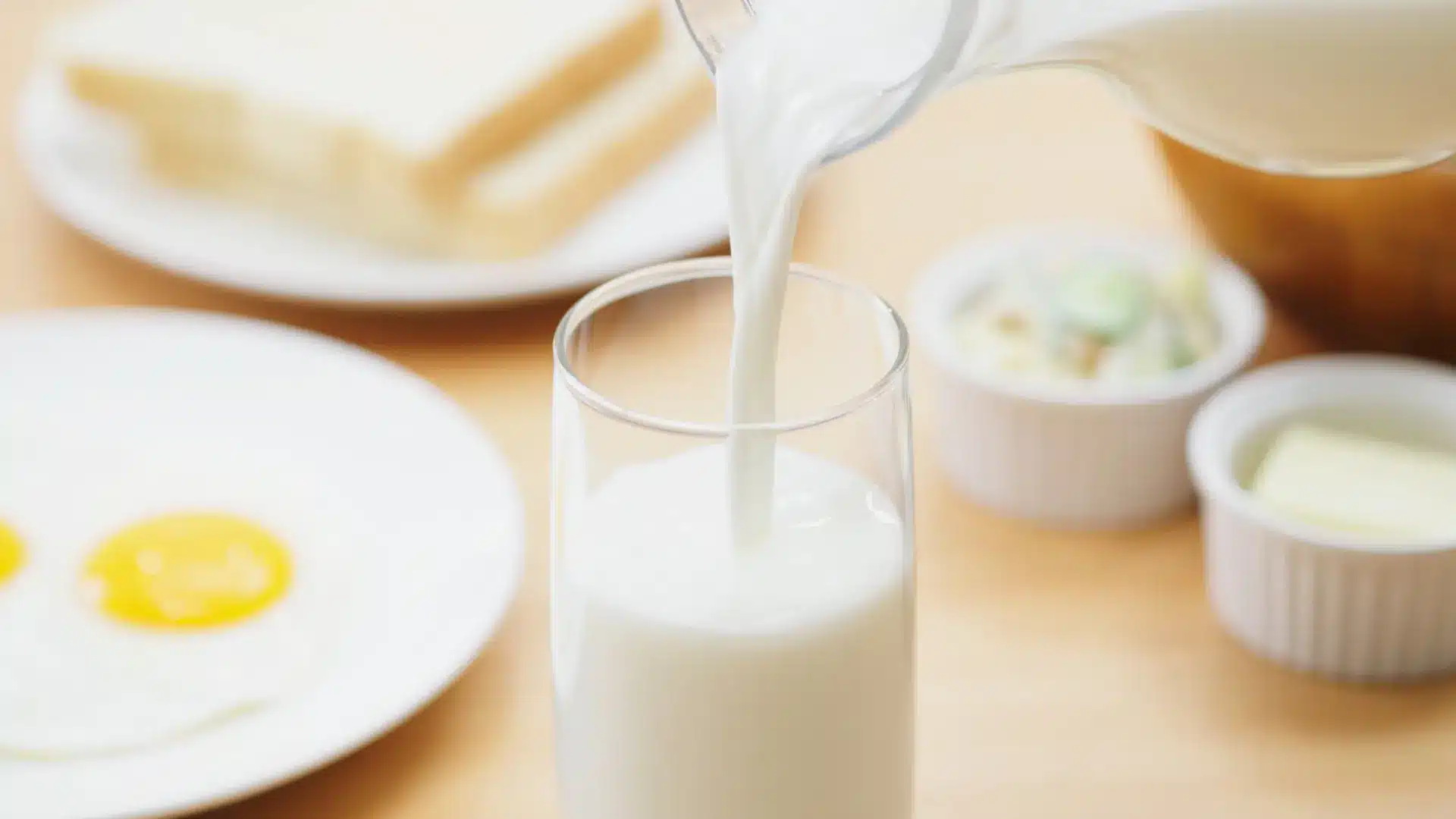 warm-toned wooden sauna featuring tiered benches, soft corner lighting, a traditional bucket with a ladle, and hot stones
