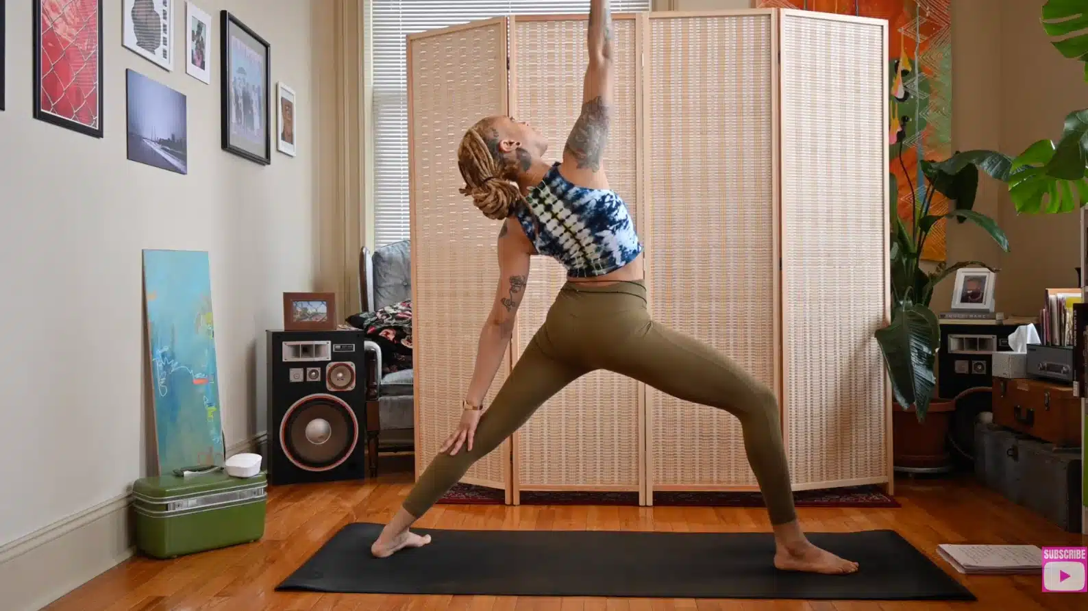 woman performing reverse warrior yoga pose with front arm reaching upward and back hand resting on leg indoors at home