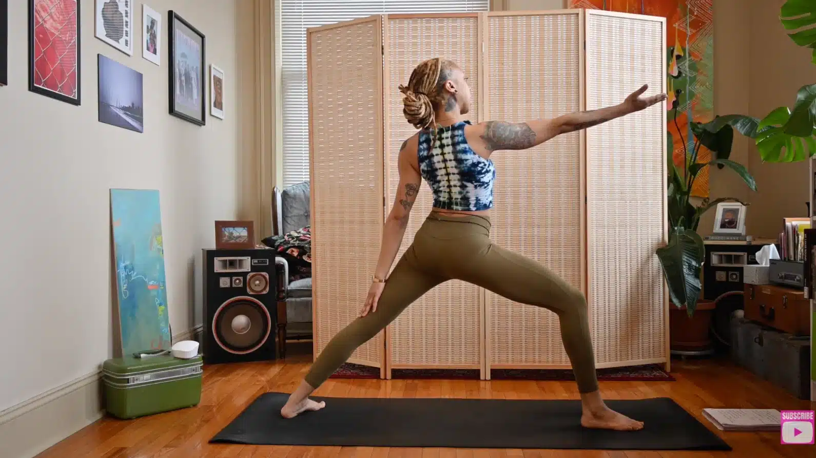 woman transitioning from warrior two into reverse warrior yoga pose with front palm flipped upward in home studio setting