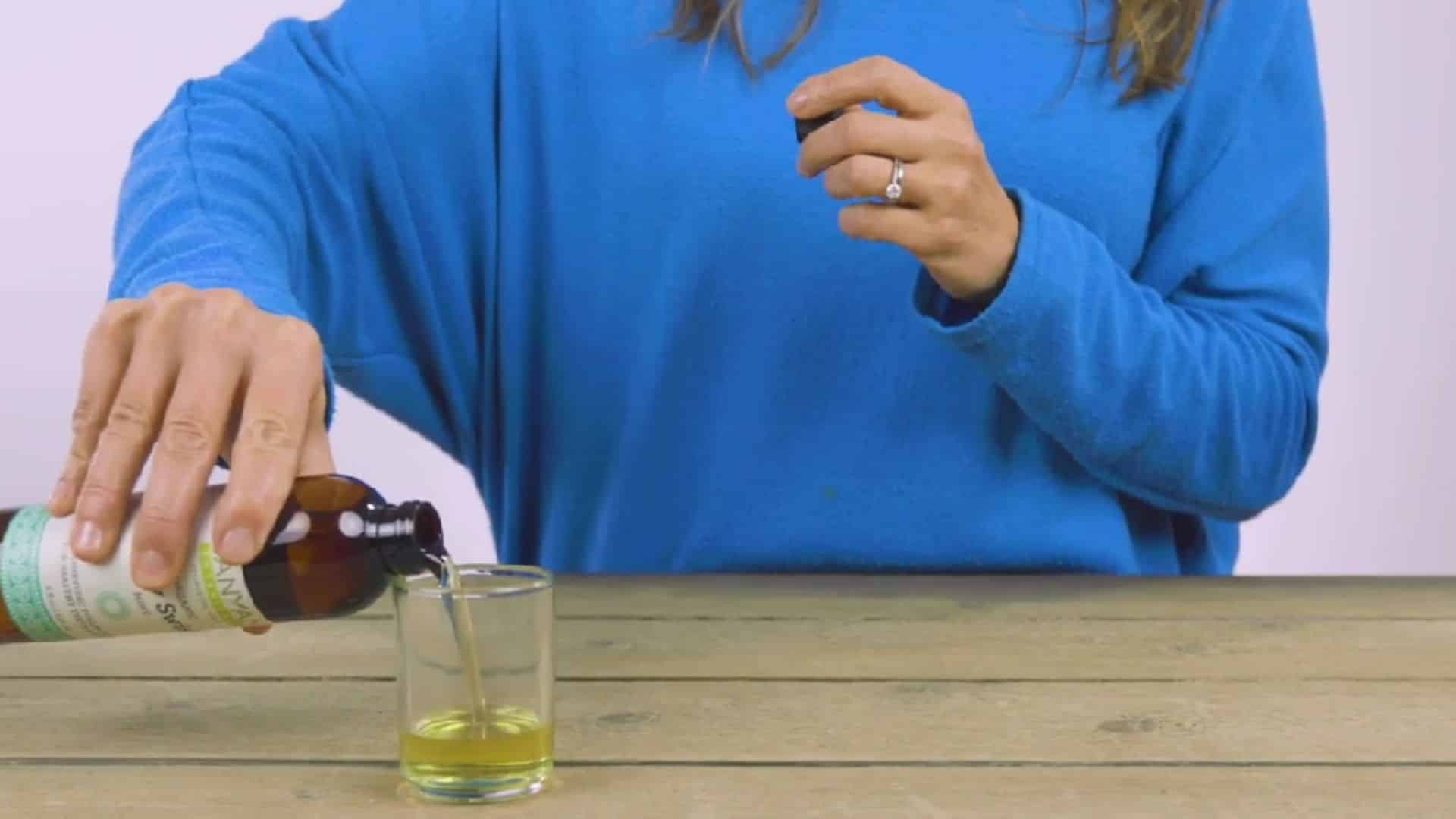 a clean glass holding one teaspoon of sesame or coconut oil measured out before an oil pulling session