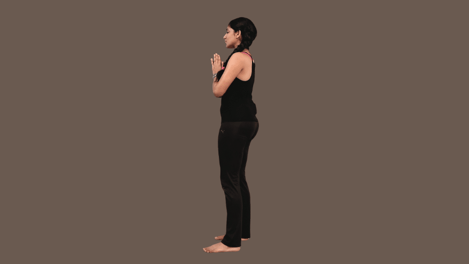 a woman doing pranamasana as a part of the surya namaskar series