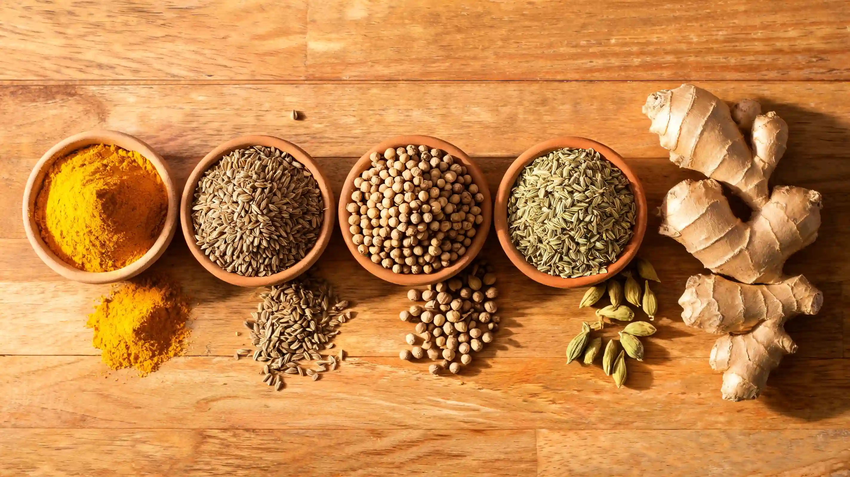 assorted herbs and spices arranged in small bowls on wooden surface