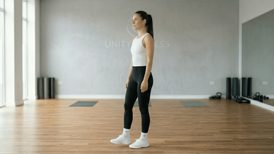 athletic woman slowly lowering her foot back to the floor after completing a single-leg captain morgan hold