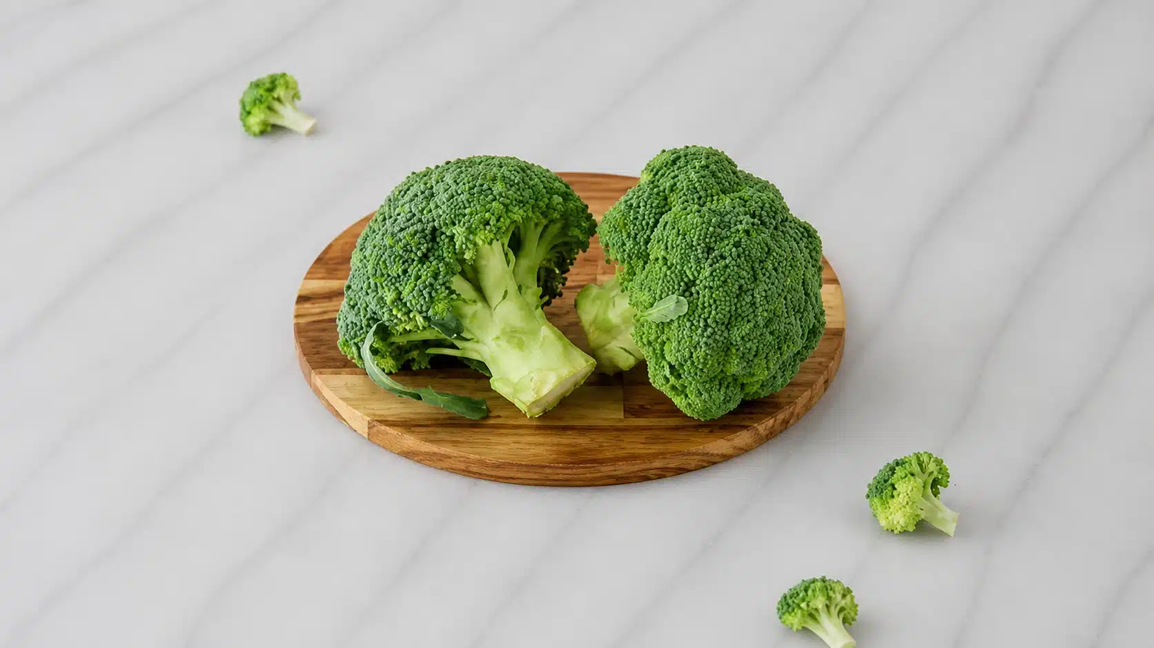 fresh broccoli florets on marble surface with soft natural kitchen lighting