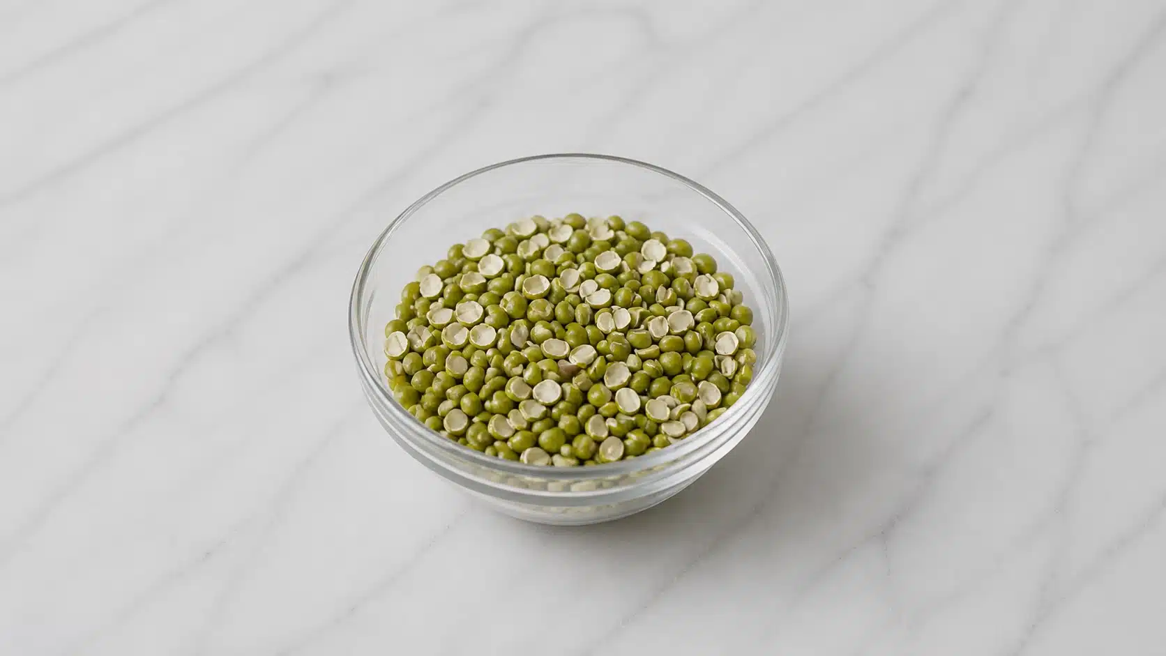 green lentils in a bowl on marble surface with natural light