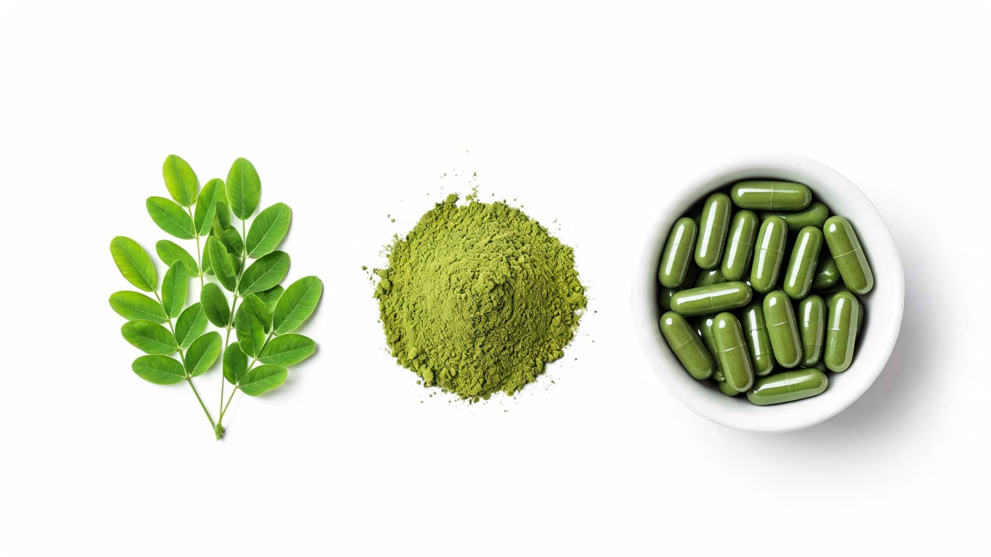 Green moringa leaves, a pile of moringa powder, and green moringa capsules in a bowl
