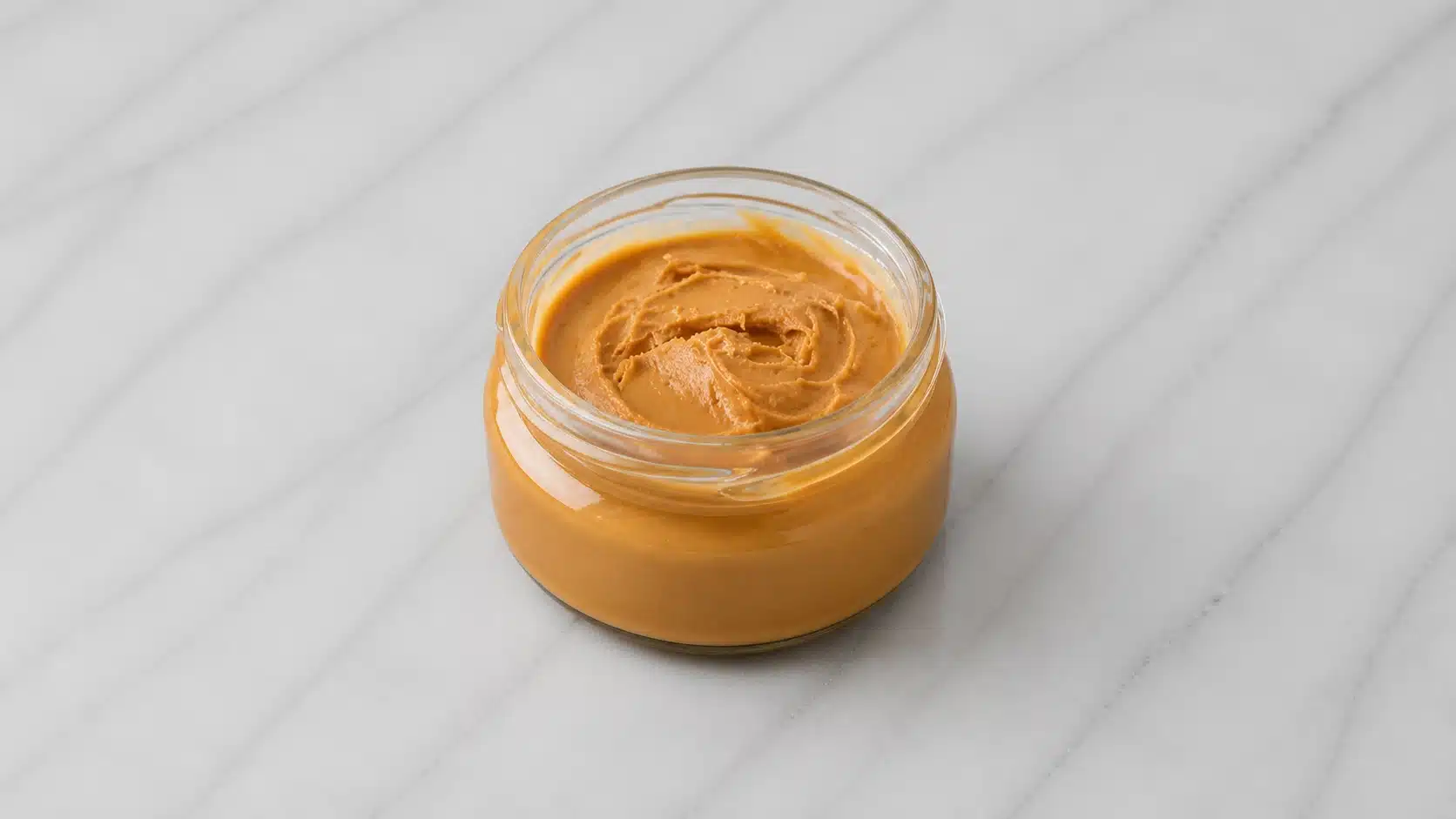 peanut butter in glass jar on marble surface with soft light
