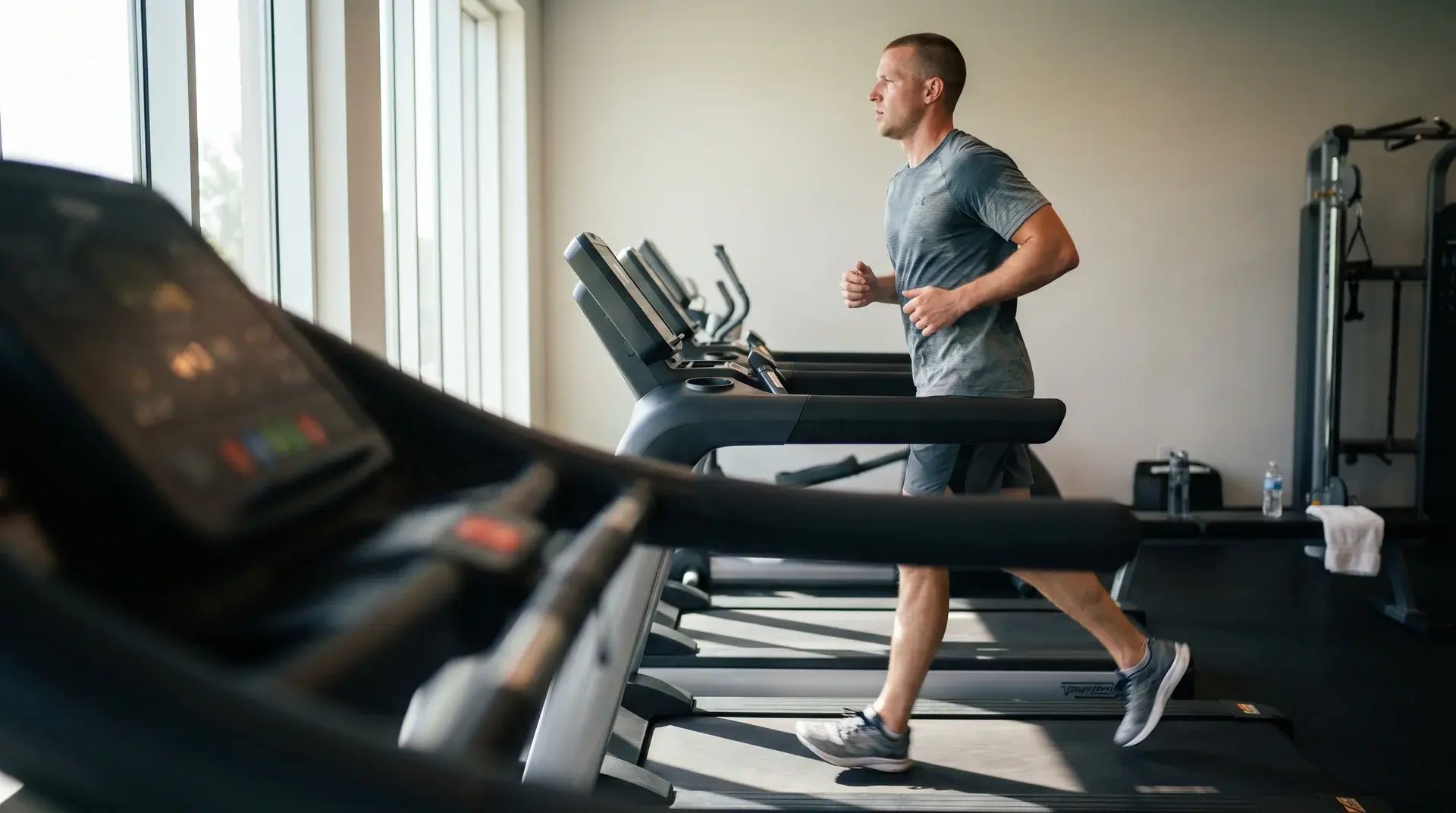 runner doing a controlled treadmill hiit interval in a bright gym with steady form and visible treadmill setup (1)