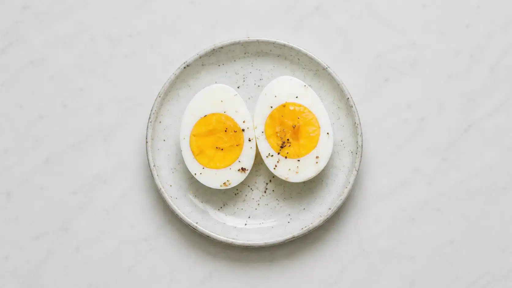 sliced boiled eggs on a white plate on marble background