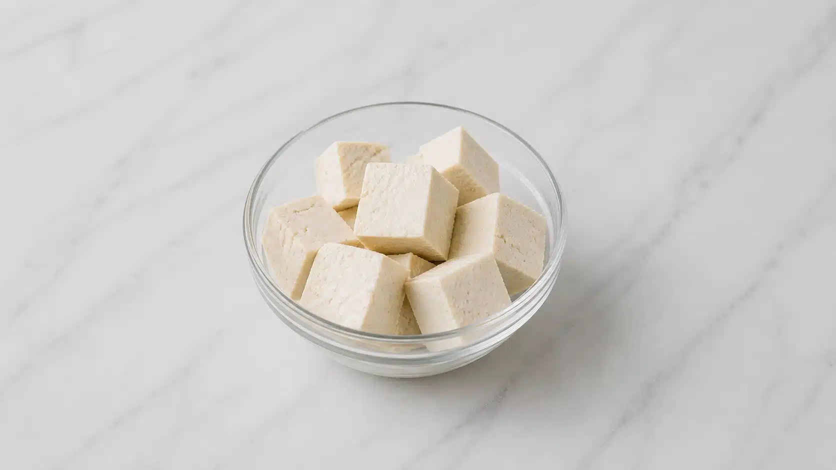 tofu cubes in a bowl on marble surface with soft light
