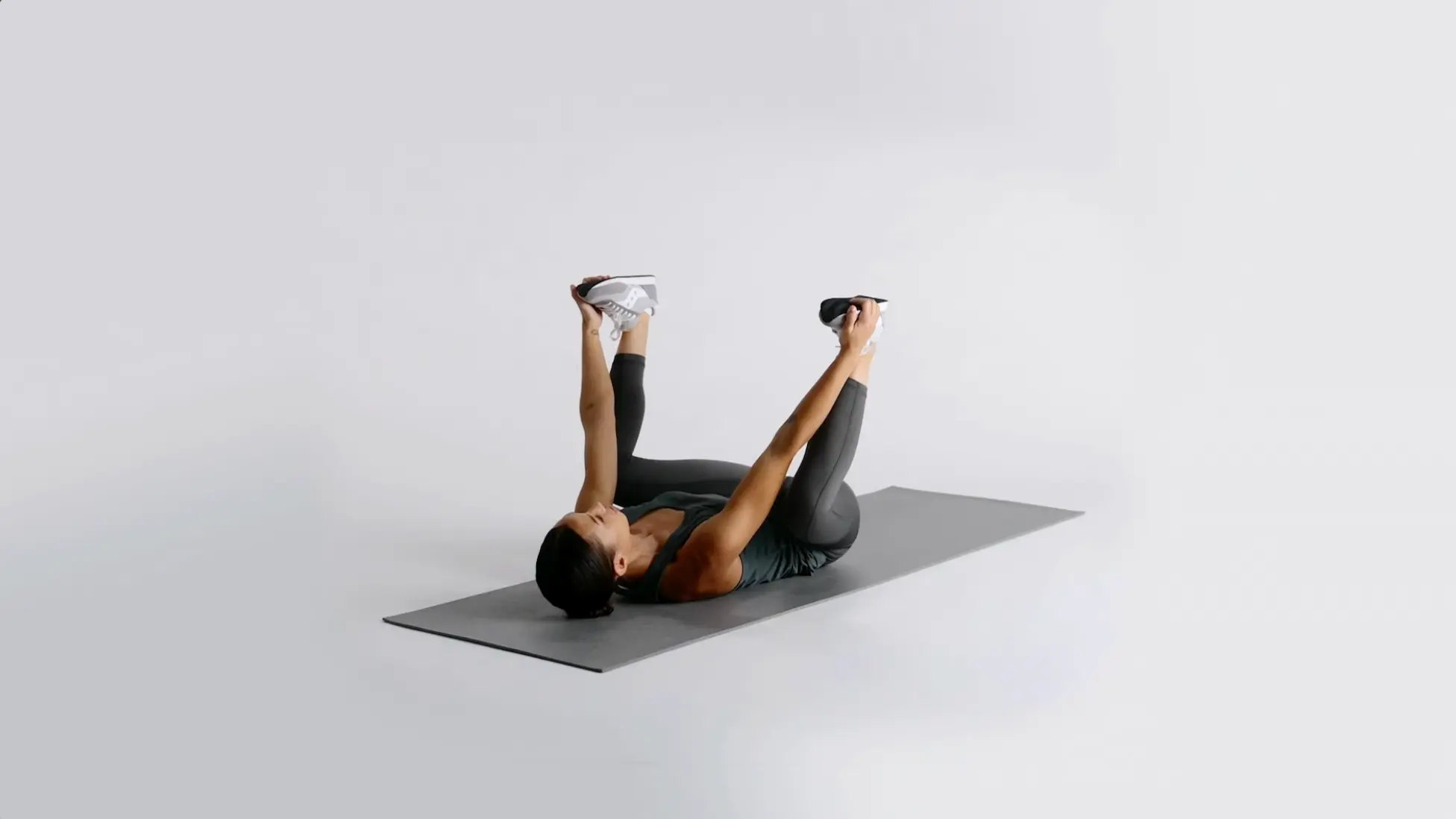 woman holding happy baby pose on a yoga mat with relaxed shoulders and steady breathing