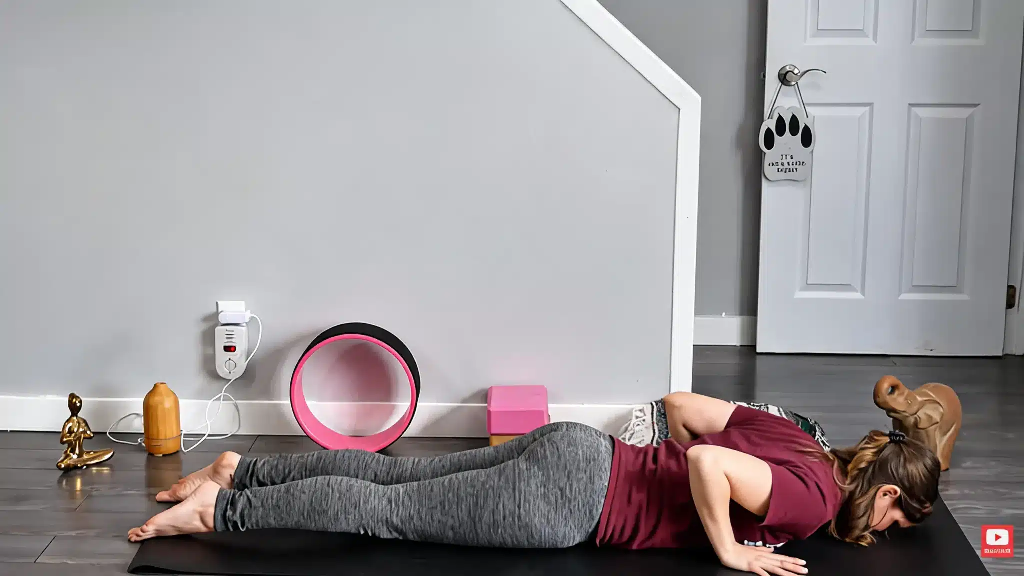 woman lying face down on a black yoga mat in starting position before baby cobra pose with forehead resting down