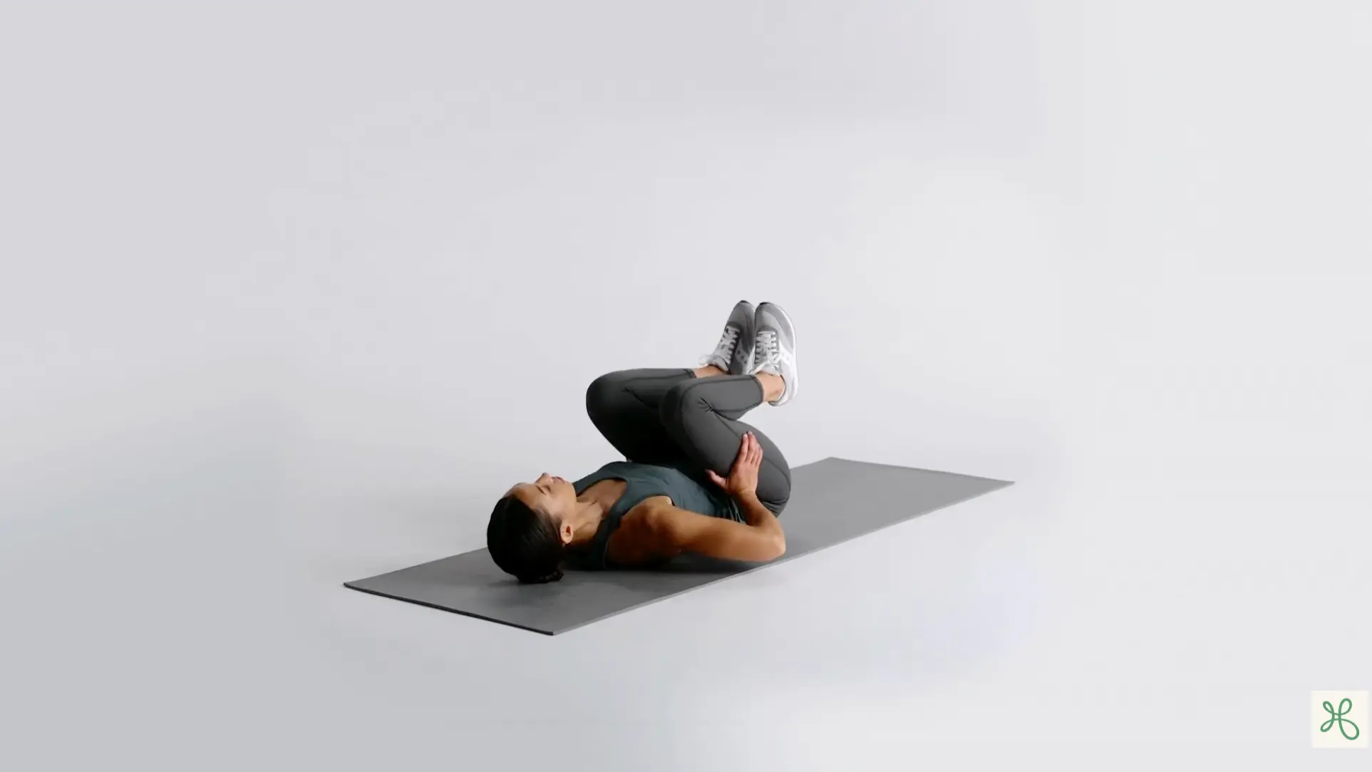 woman lying on a yoga mat holding the outer edges of her feet in happy baby pose