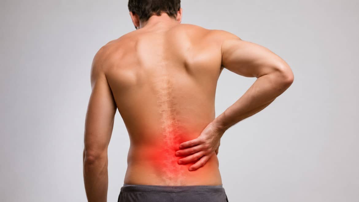A man with back pain holds his lower back with one hand, highlighting the spine pain