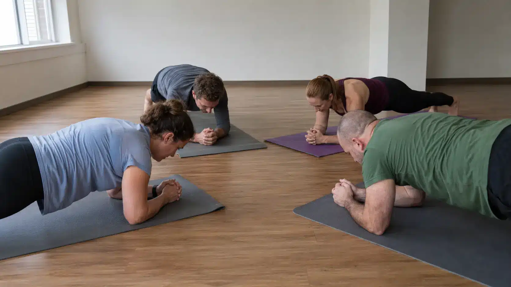 four people in plank position arranged in a square box formation during group yoga
