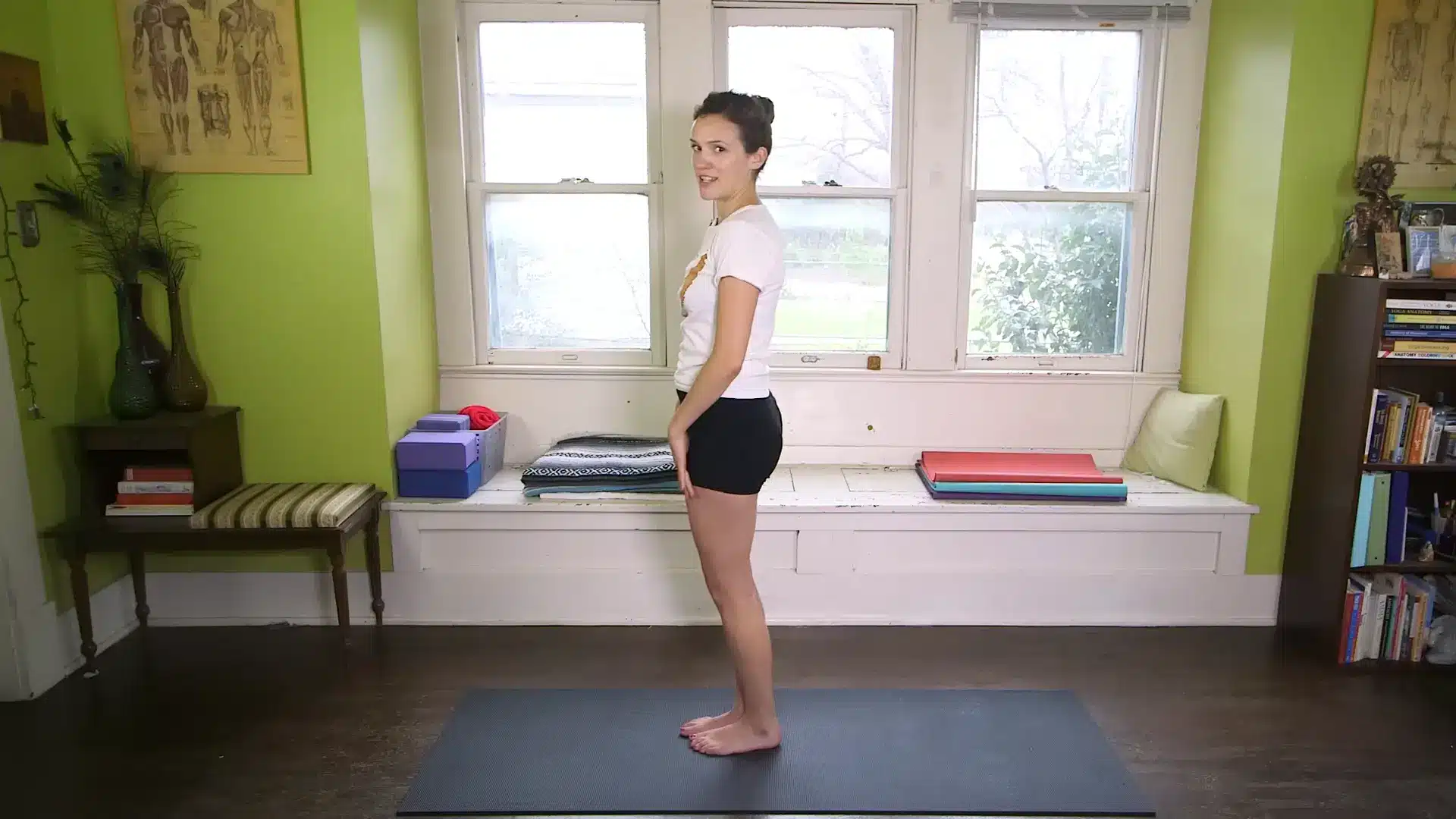 person standing in relaxing pose on yoga mat in a bright home yoga room after practice
