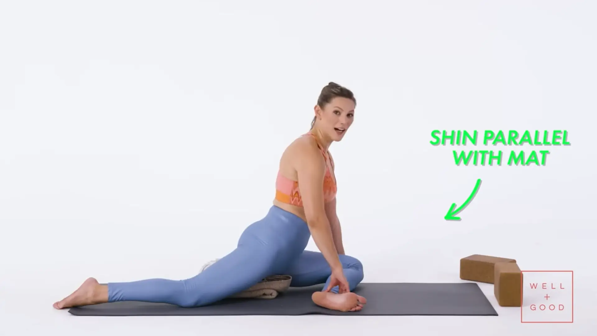 person using a yoga block under the front hip for supported pigeon pose alignment