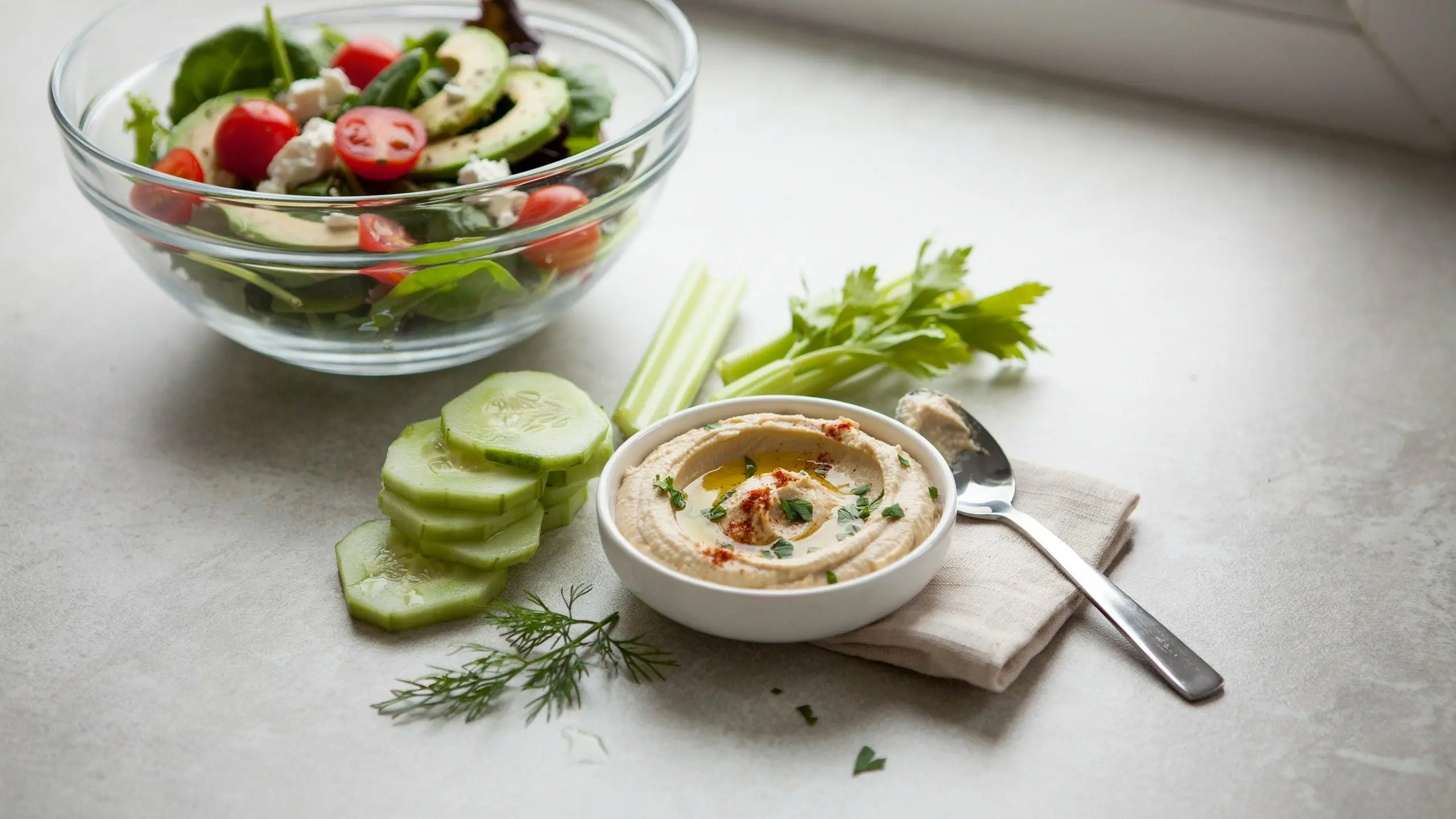 small hummus serving with cucumber celery and keto salad in morning light