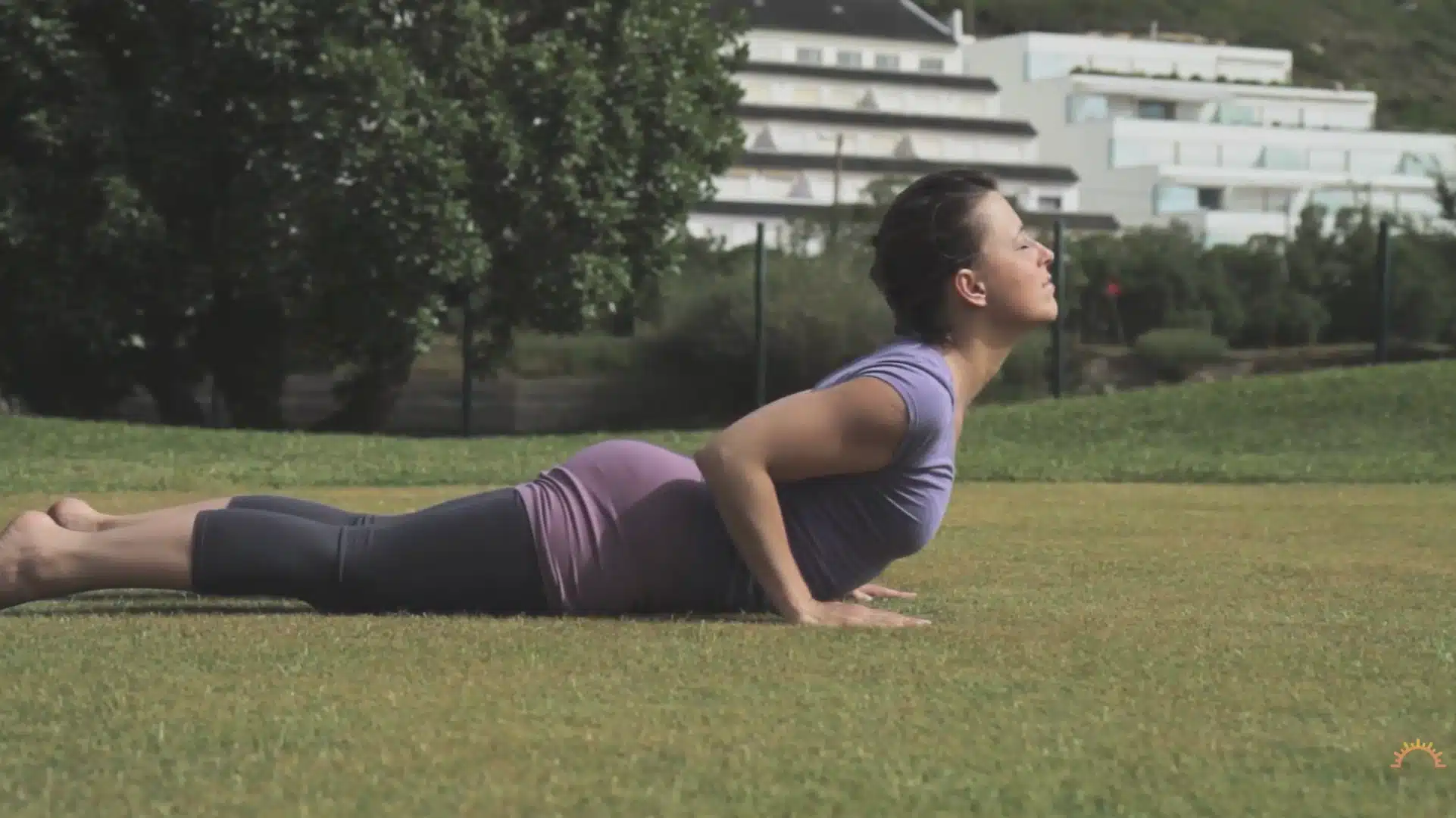 woman lifts chest into cobra pose outdoors during a steady yoga flow on grass