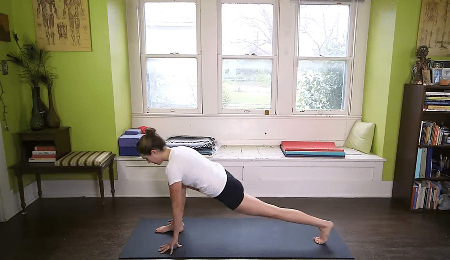 Person doing yoga lunge pose on mat in bright home studio