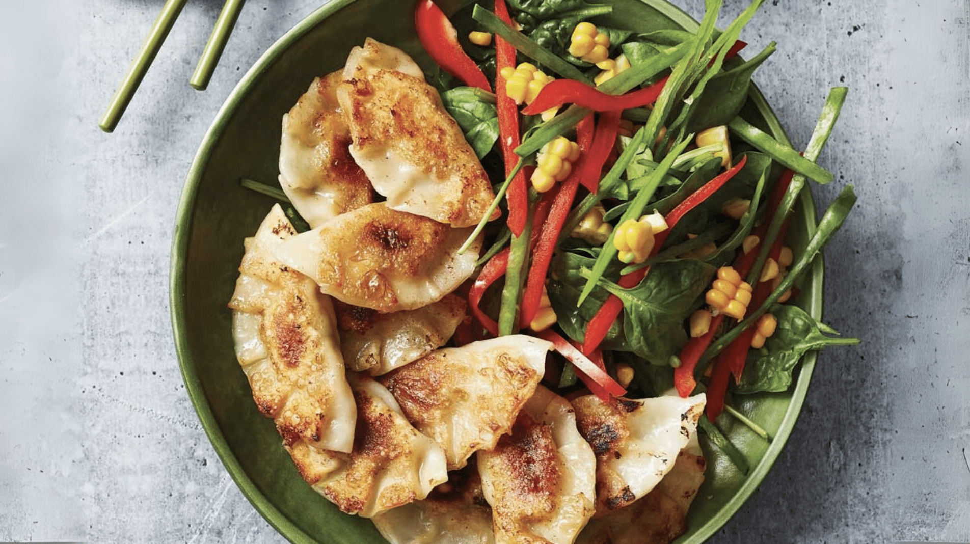pan-fried dumplings served with spinach, corn, red peppers, and greens in a bowl for a balanced meal