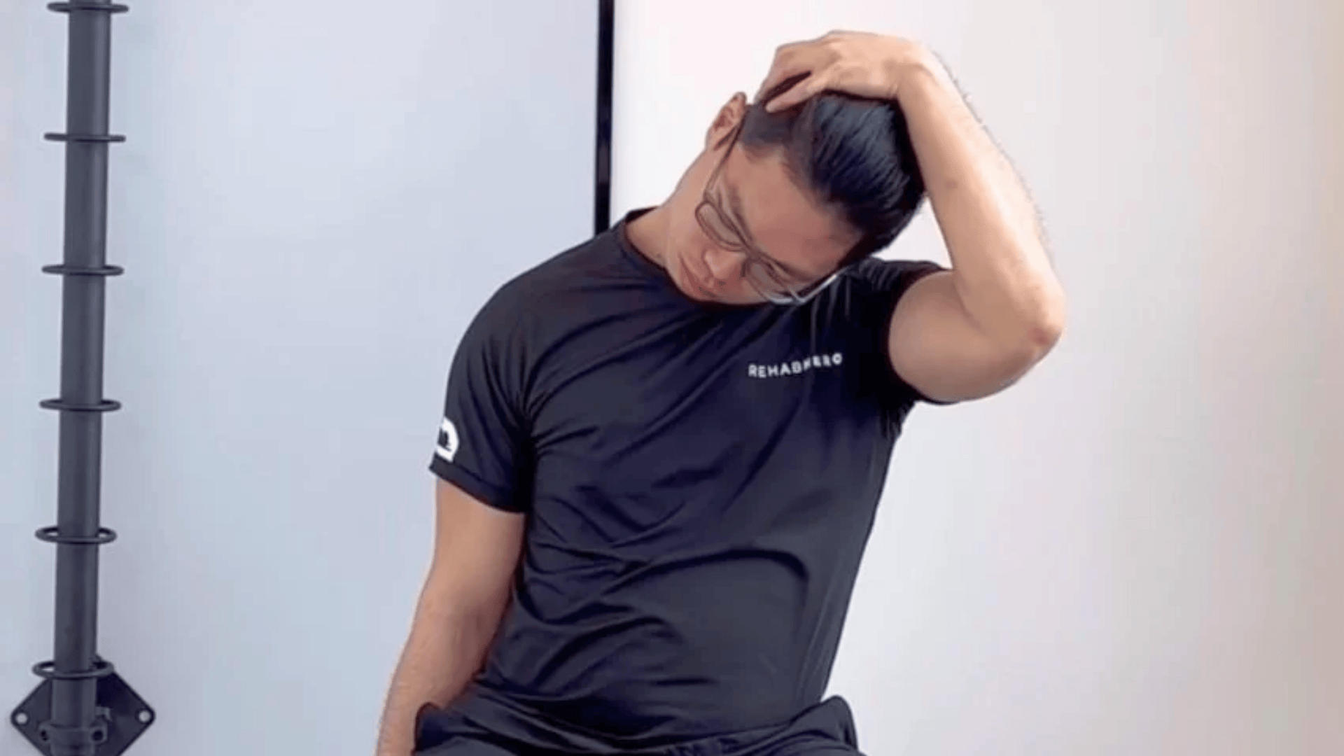 man seated and gently pulling head to the side for an upper trapezius neck stretch
