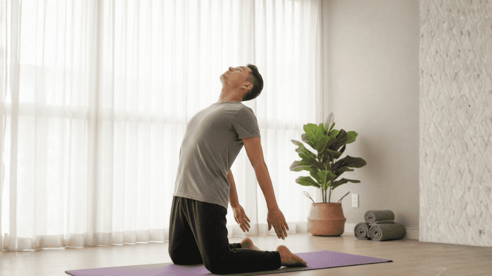 A person practicing yoga in a bright, minimalist room, performing the Camel Pose with a peaceful expression