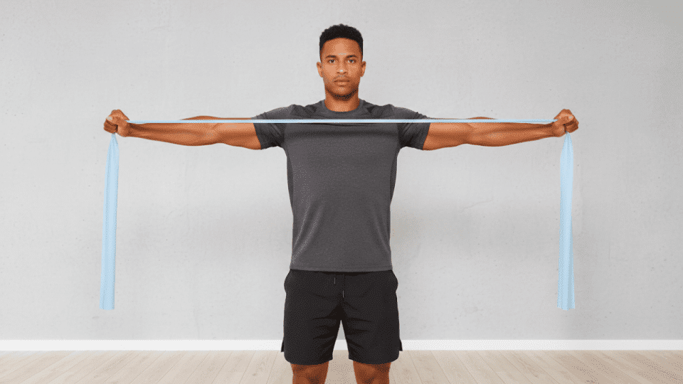 A man performing a resistance band exercise,holding the band at shoulder width,focusing on strength training