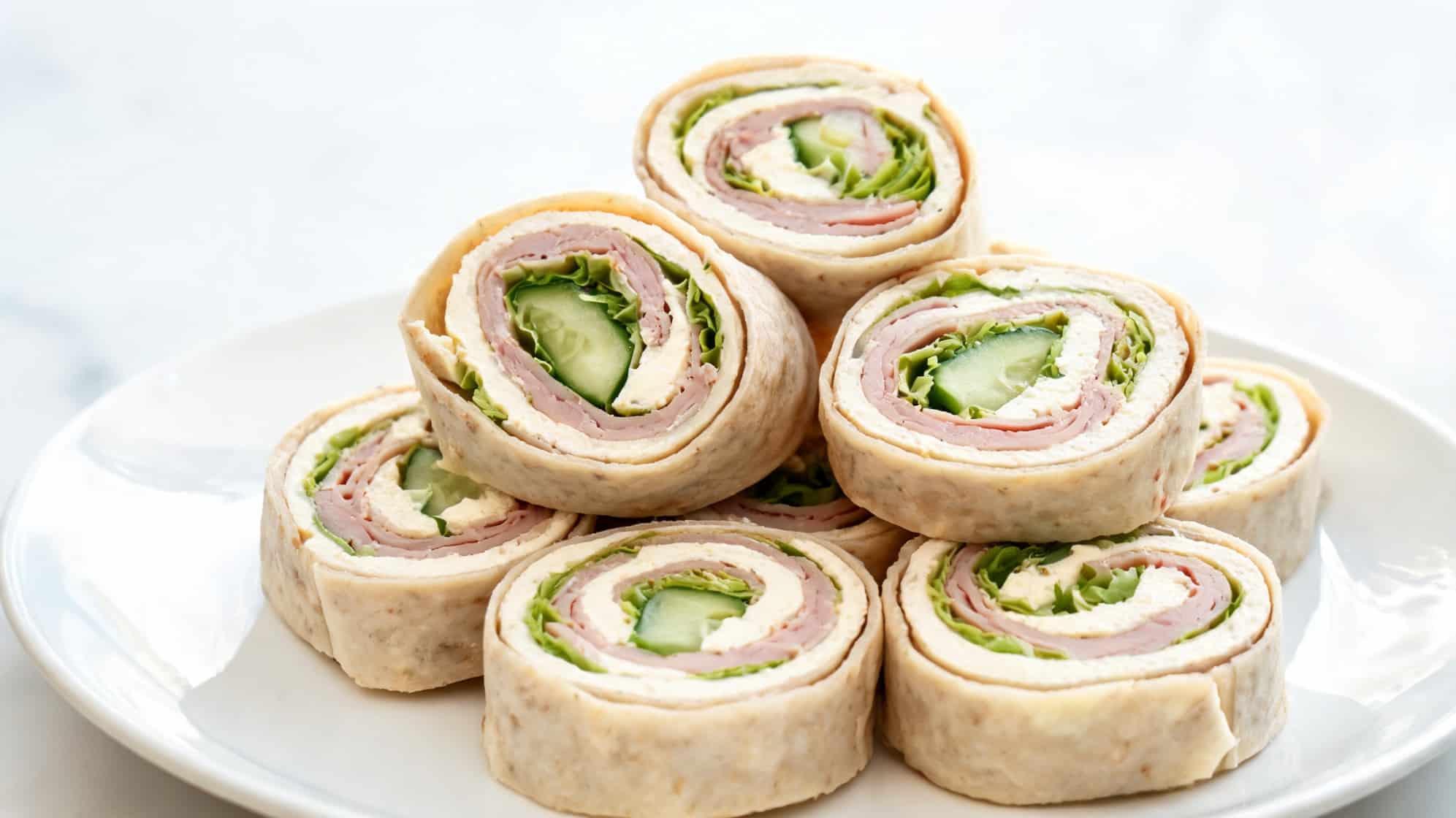 A stack of pinwheel sandwiches. The swirls show layers of ham, lettuce, cucumber, and cream cheese (1)