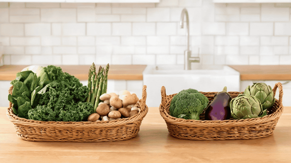 Assorted low carb vegetables including broccoli, spinach, cauliflower, zucchini, asparagus, and Brussels sprouts on a kitchen table