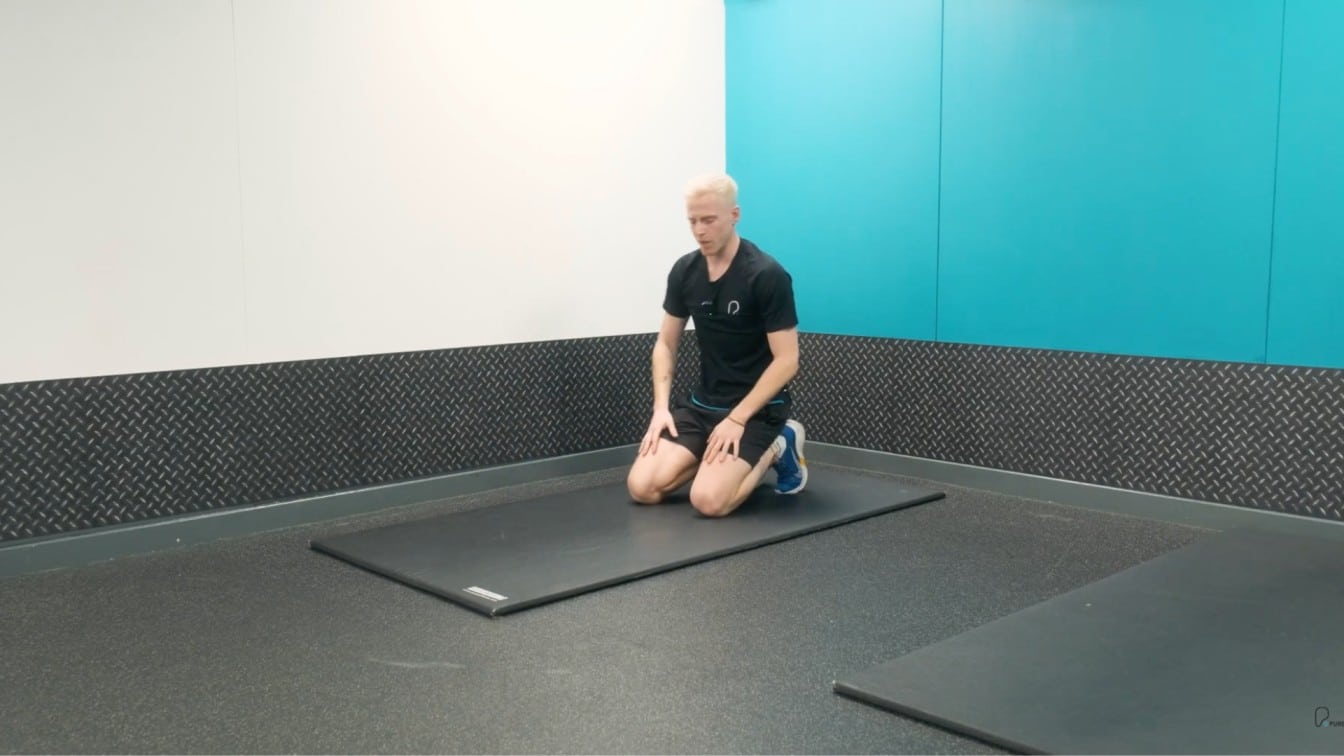 instructor kneels on the mat before starting the pose.