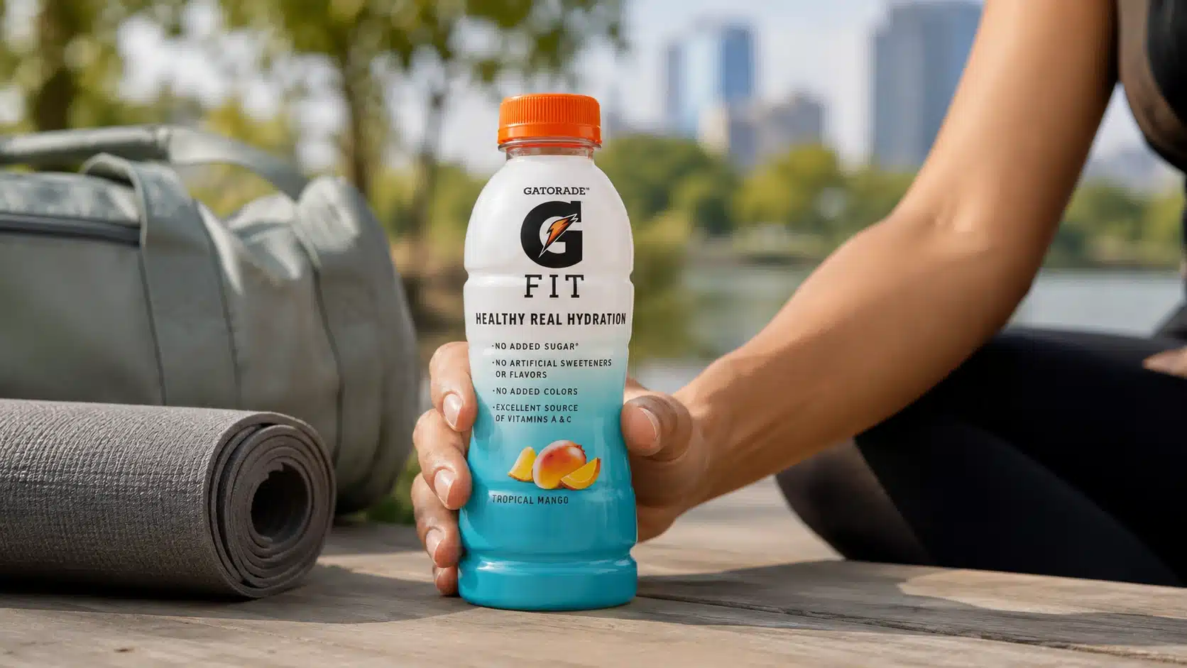 adult hand setting gatorade fit on a picnic table after a walk with fruit nearby