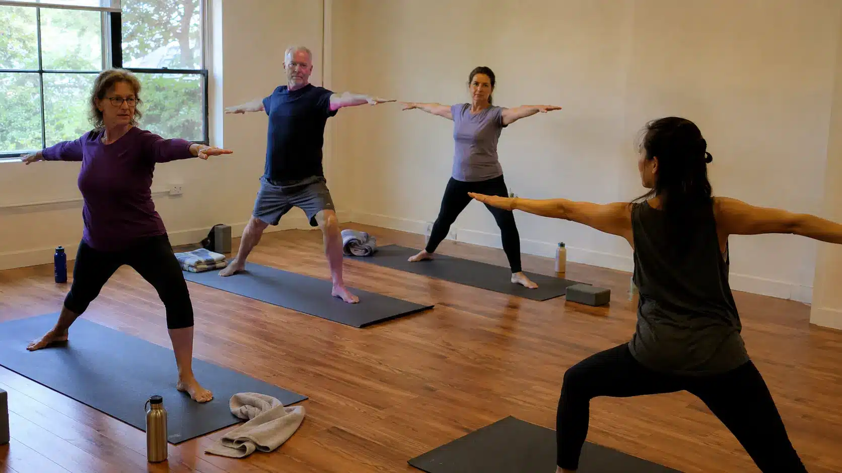 four people practicing 4 person yoga poses in a calm yoga studio