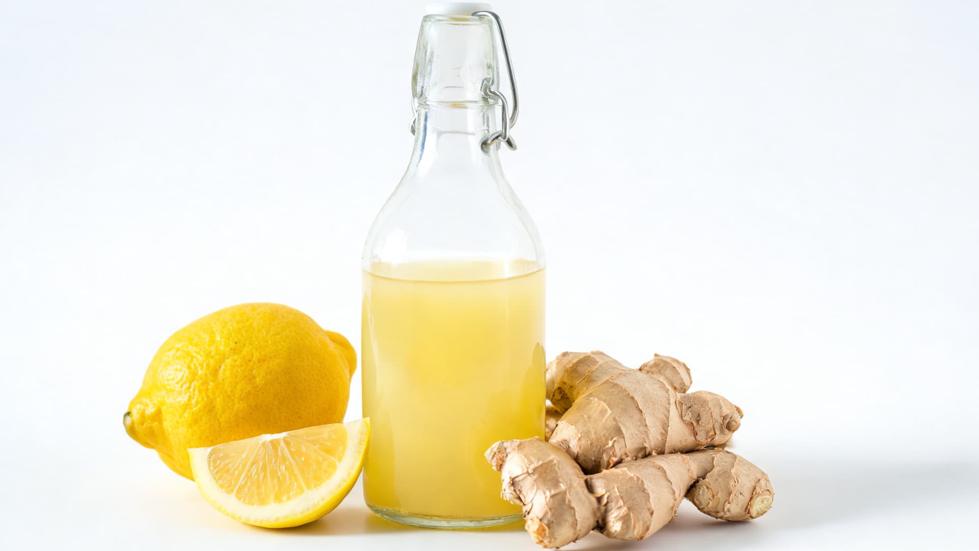 fresh lemon ginger juice in glass bottle with lemon and ginger on clean white background