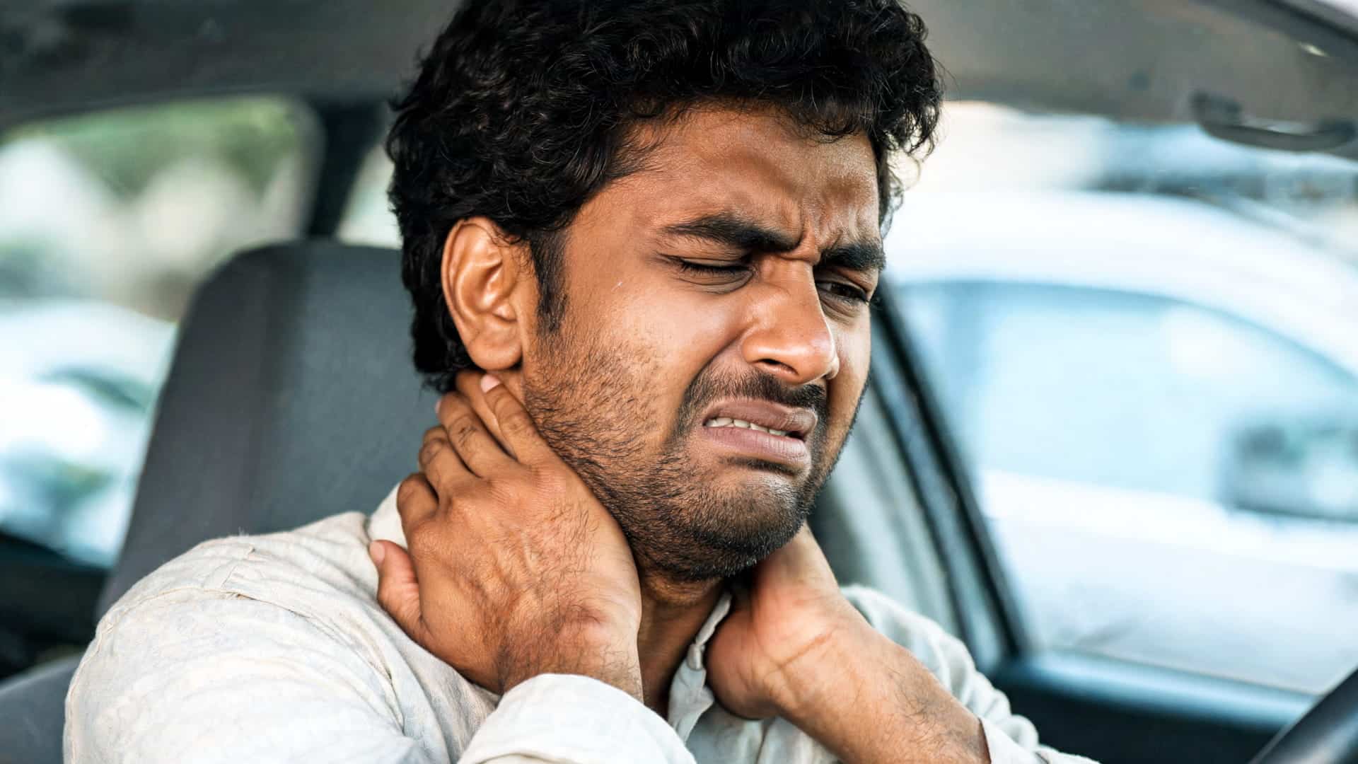 indian man experiencing whiplash neck pain after a car accident