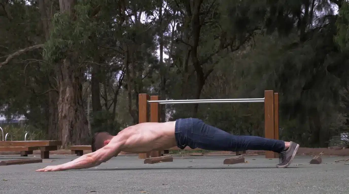 man performing an extended rollout style core drill outdoors with arms reaching forward and body aligned