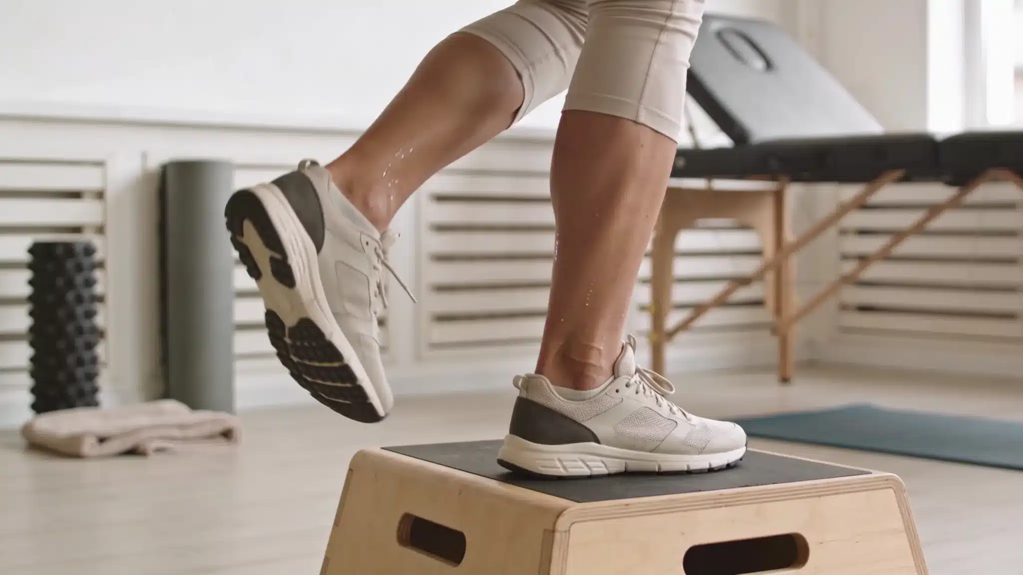 person doing controlled heel drop on a step with achilles tendon focus in a calm rehab setting