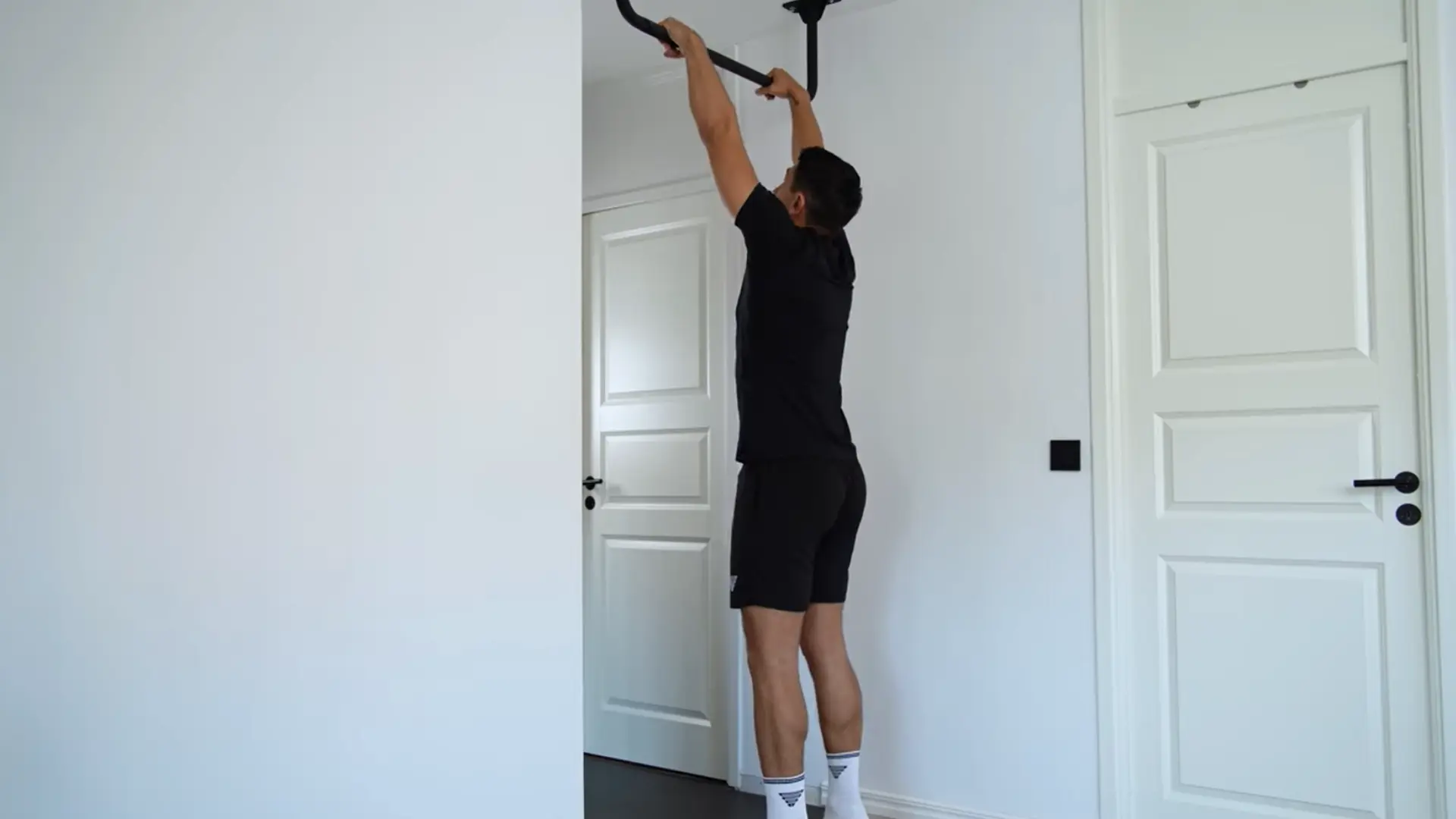 person gripping a pull-up bar slightly wider than shoulders with palms neutral to keep wrists comfortable