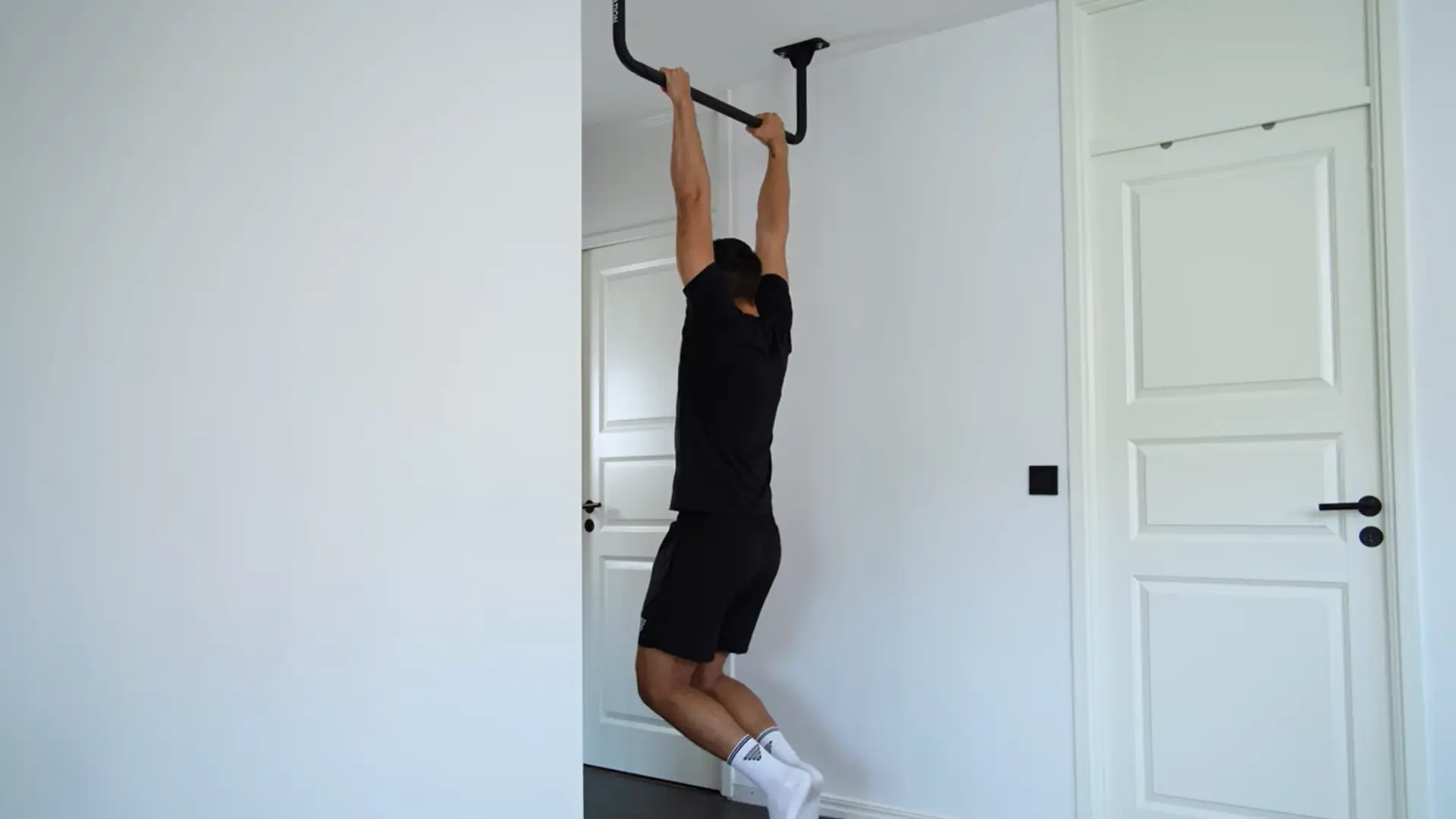 person hanging from a pull-up bar with straight back, open chest, shoulders relaxed, core lightly engaged, and hands holding bar