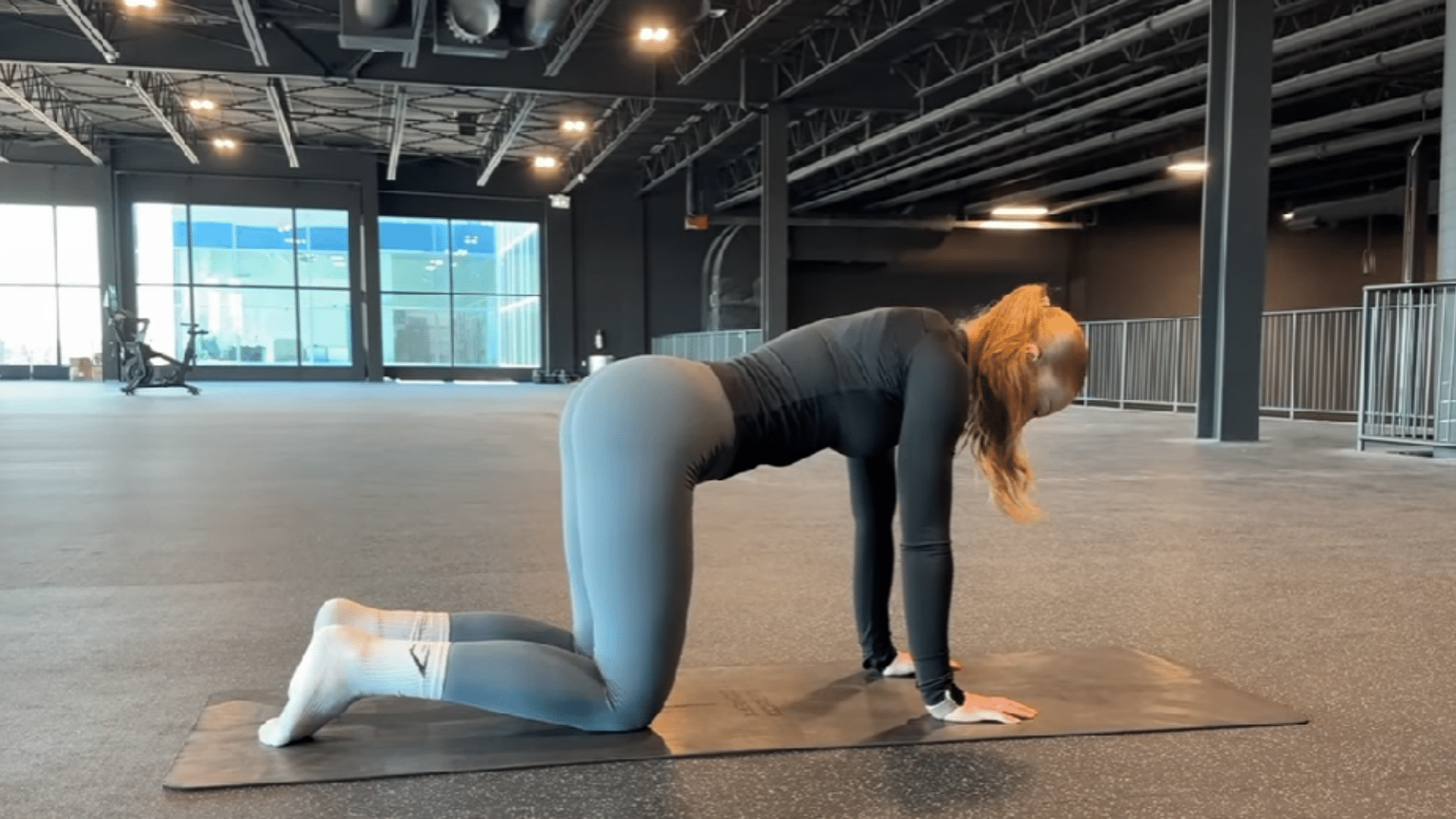 Person in all fours position on a yoga mat preparing for donkey kicks